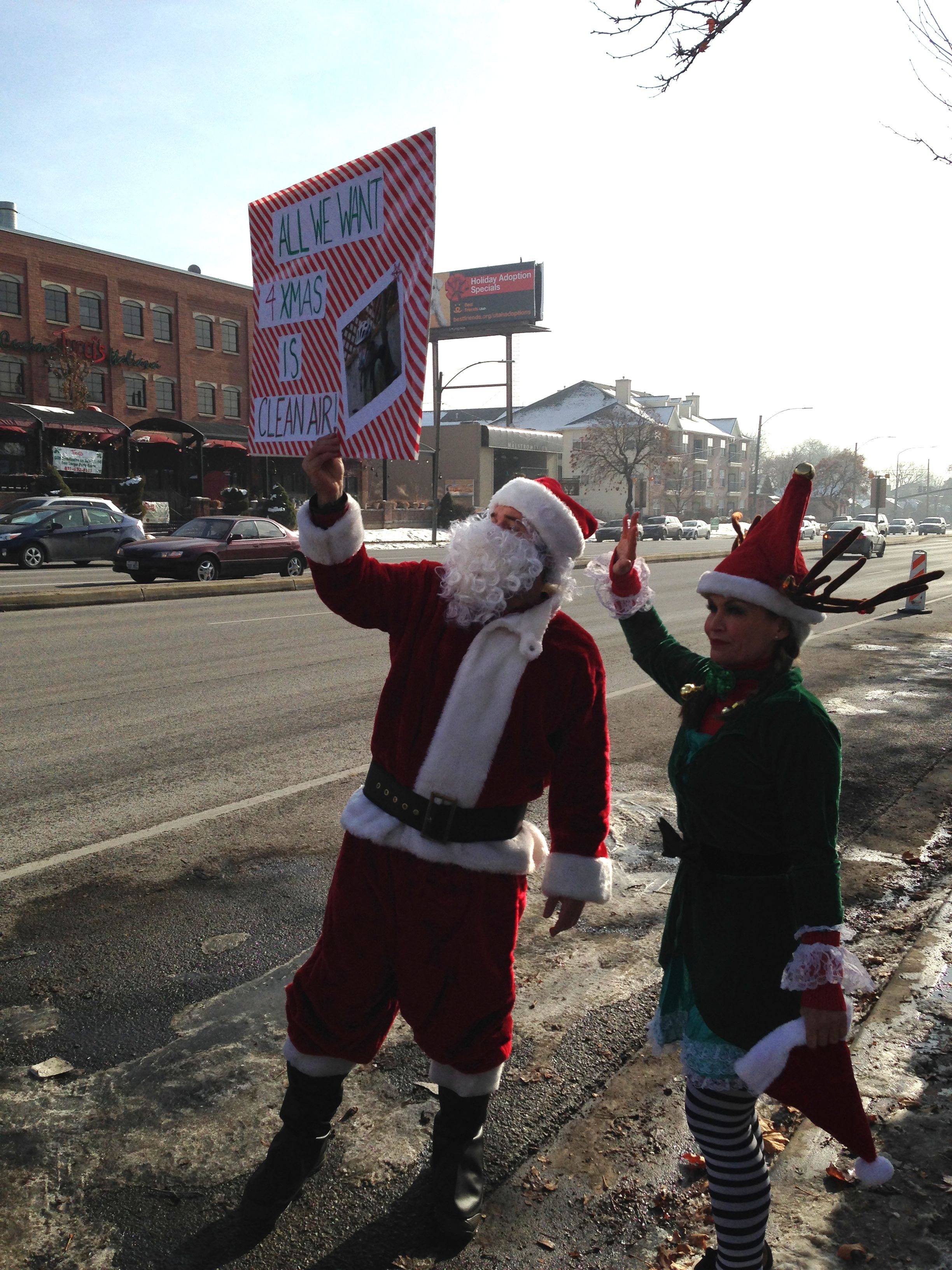 Clean air protesters dressed as Santa and an elf wave to passing cars outside Trolley Square.
